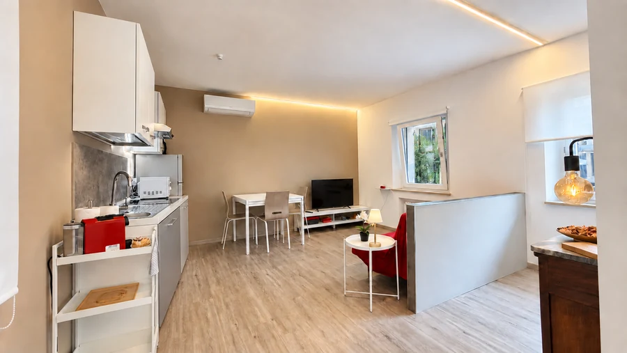 Zona giorno di Alkecè Red vista dalla cucina, con tavolo da pranzo e TV