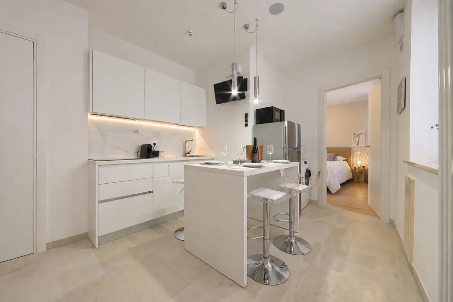 Cucina completa con penisola di Alkecè Silver, con la camera matrimoniale sullo sfondo