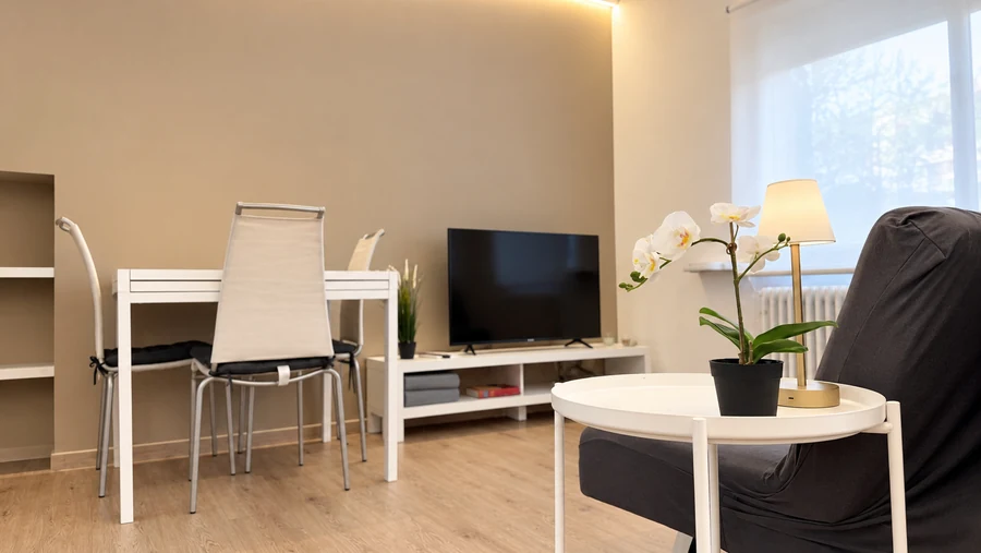 Tavolo da pranzo, TV e tavolino con orchidea nella zona giorno di Alkecè White